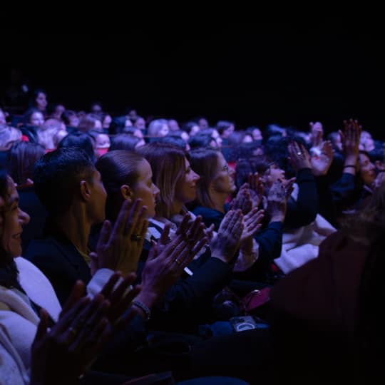 Women clapping while listening to orator.