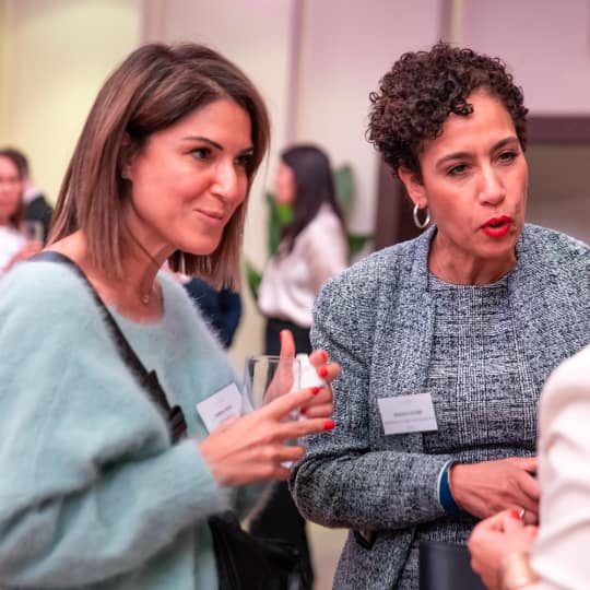 2 women attendees talking with a 3rd woman.